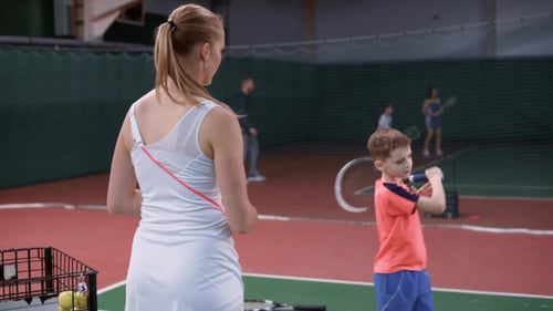 Woman and Boy Practicing Tennis on Indoor Court