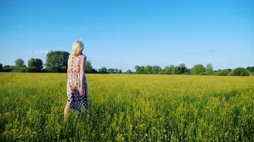 Young Woman Walking on a Flowering Meadow