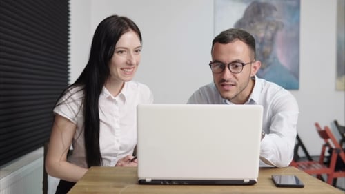 Business People Looking at Laptop Screen and Talking in Office