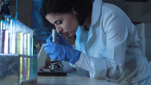 Woman Scientist Using Microscope in Laboratory