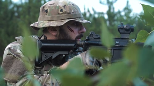Soldier Aims Rifle in Wilderness Environment
