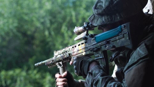 Camouflage Rifle Held in Forest Setting
