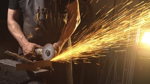 Tradesman Grinding Metal With Angle Grinder Indoors
