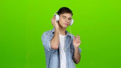 Guy Listens To the Music in the Headphones and Adjusts To the Positive. Green Screen