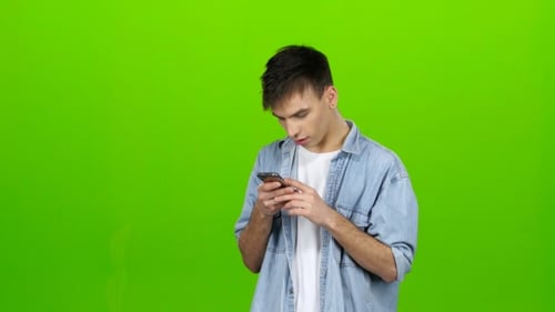 Man Looks at the Phone in the Photo, and Has Fun. Green Screen