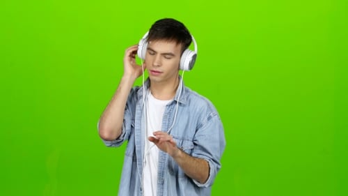 Guy Listens To the Music in the Headphones and Adjusts To the Positive. Green Screen