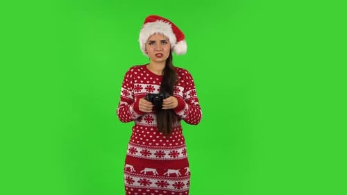 Sweety Girl in Santa Claus Hat Is Playing a Video Game Using a Wireless Controller and Loses. Green