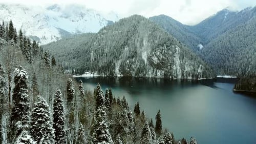 Aerial view of deep alpine lake with blue water, surrounded by mountains.