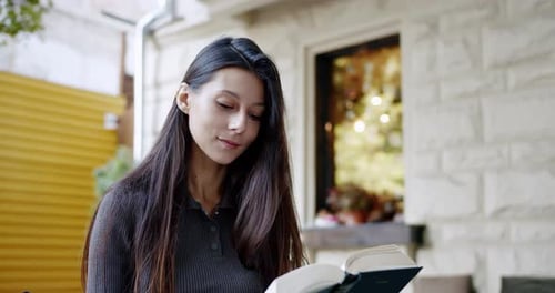 Young Woman Reading Book in Cafe Setting