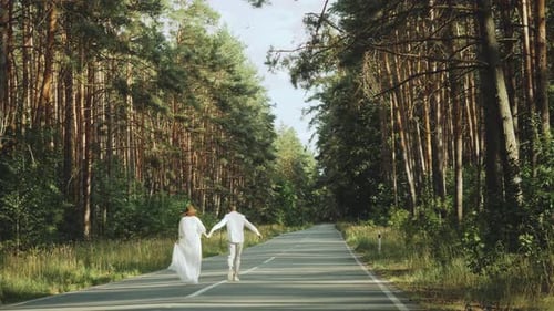 A Cheerful Young European Couple is Walking in a Picturesque Place in the Pine Forest with Soft