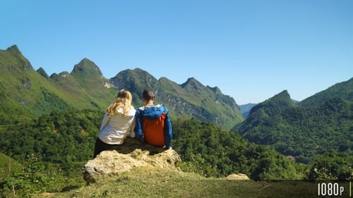 Hiking Couple Sit Down and Enjoy the Beautiful Mountain Scenery