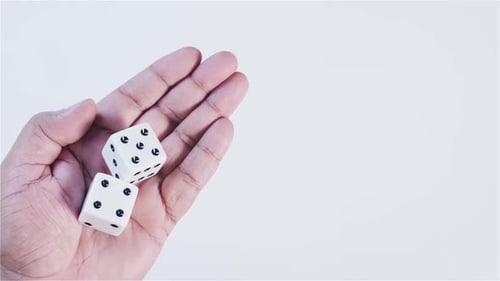 Hand Holding White Dice With Black Dots