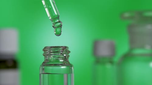 Uma gota clara de óleo de essência orgânica cai da pipeta em frasco de vidro
