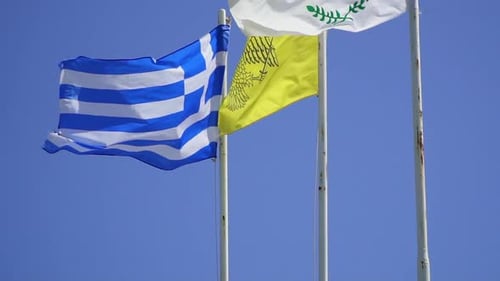 Greek and Cypriot Flags Waving Against Clear Blue Sky