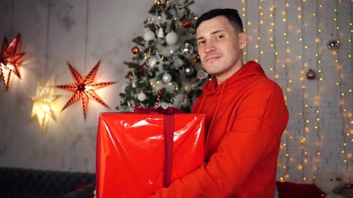 Smiling Man Holding Christmas Present in Decorated Home