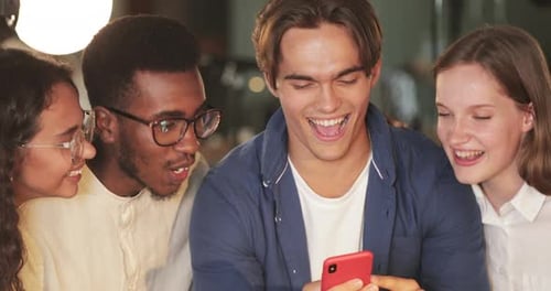 Close Up View of Multiethnic People Looking at Mobilephone Screen and Laughing. Young People Smiling