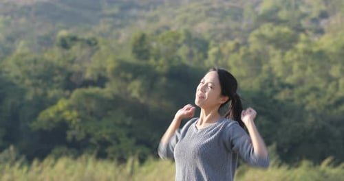 Excited woman raising hand up at outdoor