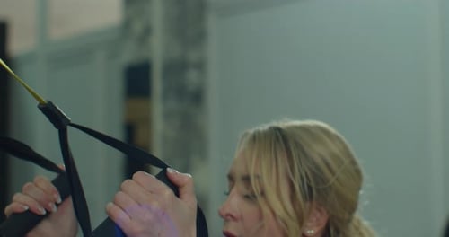 Closeup Fit Woman Trains with Strap Resistance System in a Modern Gym