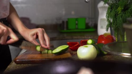 Woman Slicing a Cucumber in Kitchen