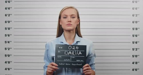 Mugshot of Beautiful Arrested Woman Holding Sign for Photo in Police Station