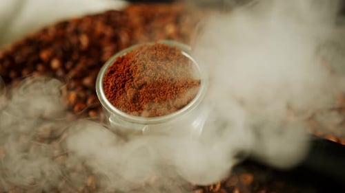 Fresh Ground Coffee Steaming over Coffee Beans