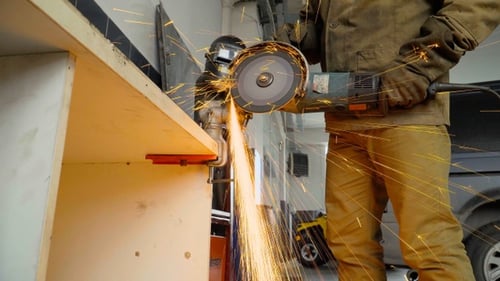 Closeup of worker using a grinder cuts metal in a workshop