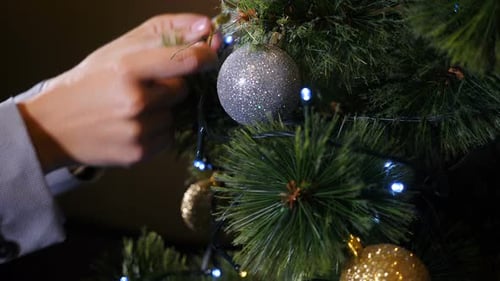 Hands Decorating Christmas Tree With Festive Ornaments