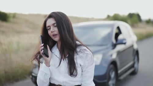Desperate Woman Taping on and Speaking on Phone at Car Out of City