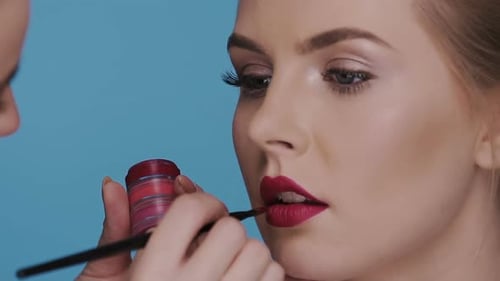 Maquillage appliqué sur le visage d'une belle femme isolée sur bleu