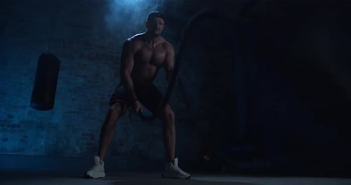 Hombre musculoso de fitness haciendo ejercicio con una cuerda de batalla abandonada