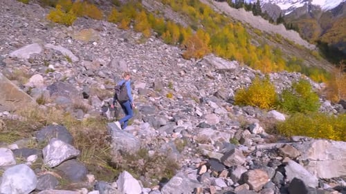 Woman Hikes Down Rocky Mountainside in Autumn