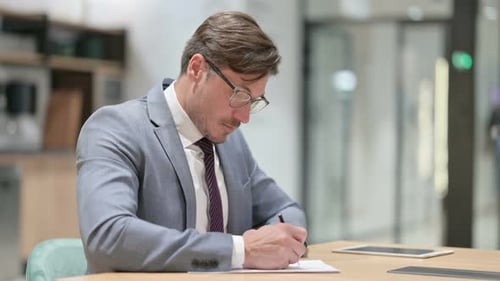 Businessman Writing on Paper in Office