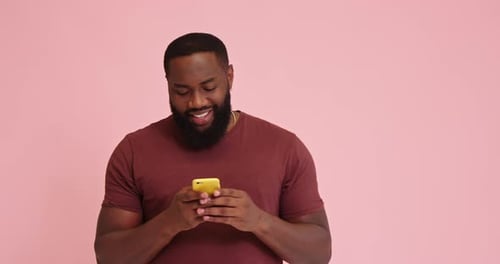 Young African American Man Use Phone Isolated on Pink Background