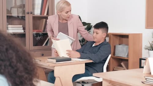 Teacher Assists Student in Classroom Reading Lesson