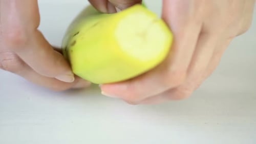 Woman Cutting Banana on White Cutting Board