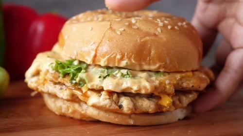 Hand Holding Beef Burger on Table Close Up
