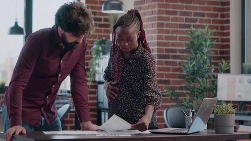 Femme attend un bébé et travaille sur un projet d'entreprise avec un collègue