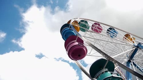 Summer Fair colorful ferris wheel set against blue sky and cloud background
