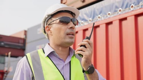 Vorarbeiter des Ingenieurs im Gespräch mit einem Kollegen im Containerlager auf einem Walkie-Talkie