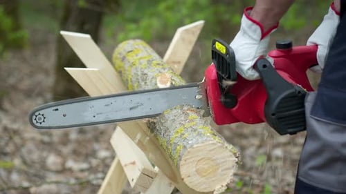 Kettensäge in Aktion beim Schneiden von Holz. Mann schneidet Baum in Baumstämme mit Säge auf Sägebock