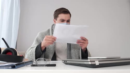 Man with mask at desk with laptop