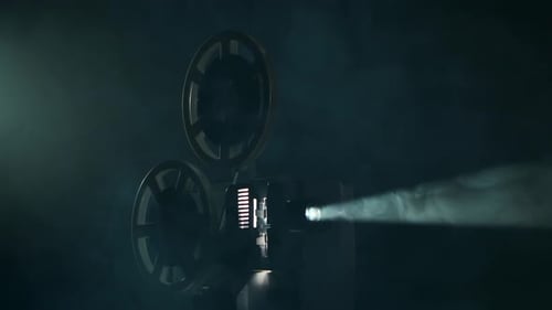 Vintage Projector Turns Film in Smoky Dark Studio. Projection Rays