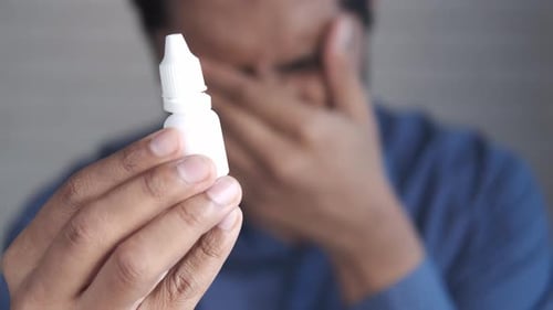 Adult Holding Bottle of Eye Drops