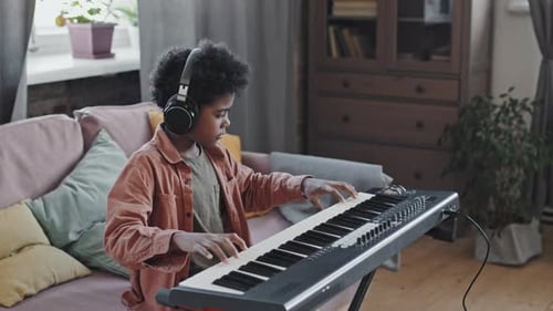 Child Plays Keyboard with Headphones in Home