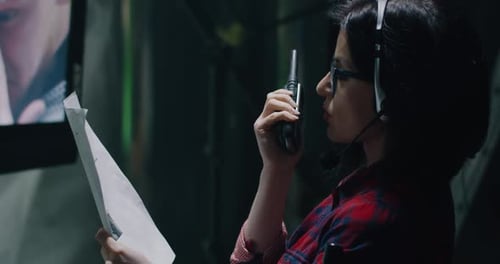 Woman Using Walkie Talkie in Control Room Environment