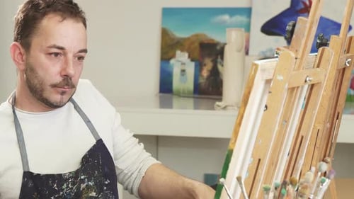 Man Painting at Easel Answers Happy Phone Call