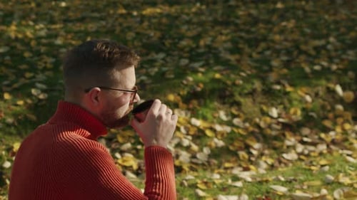 Man Enjoying Coffee in Autumn Park on Bench