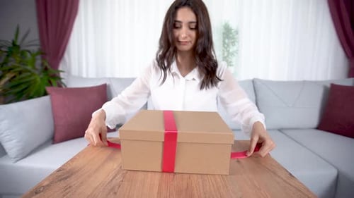 Young Woman Tying Bow on Birthday Gift Box