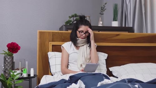 Woman in Bed with Illness Looking at Tablet