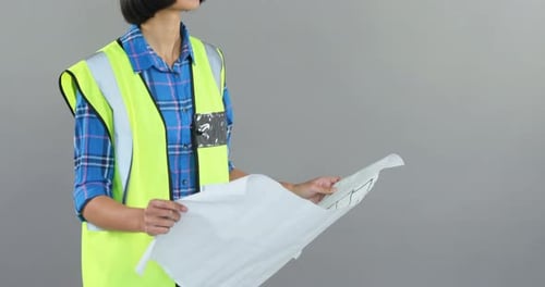 Female architect looking at blueprint against grey background 4K